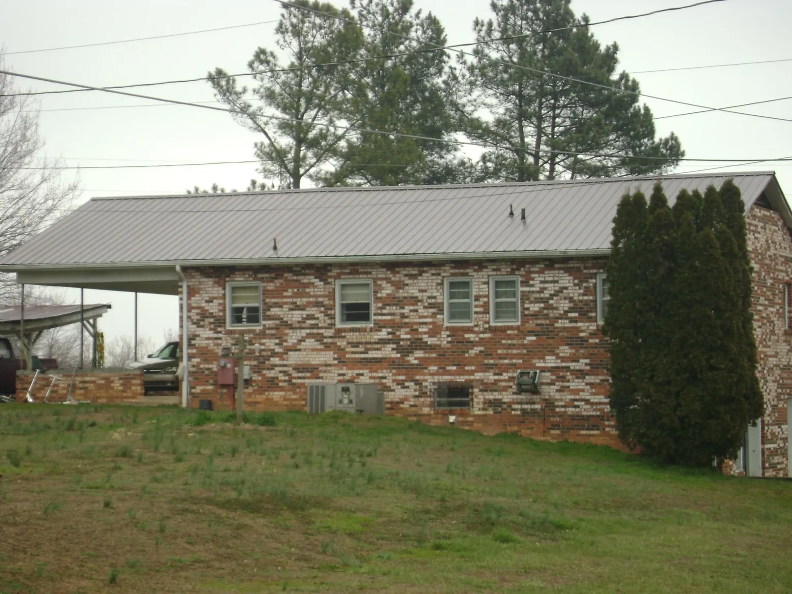 Gray metal roof on a brick split level home with a carport in Brandon