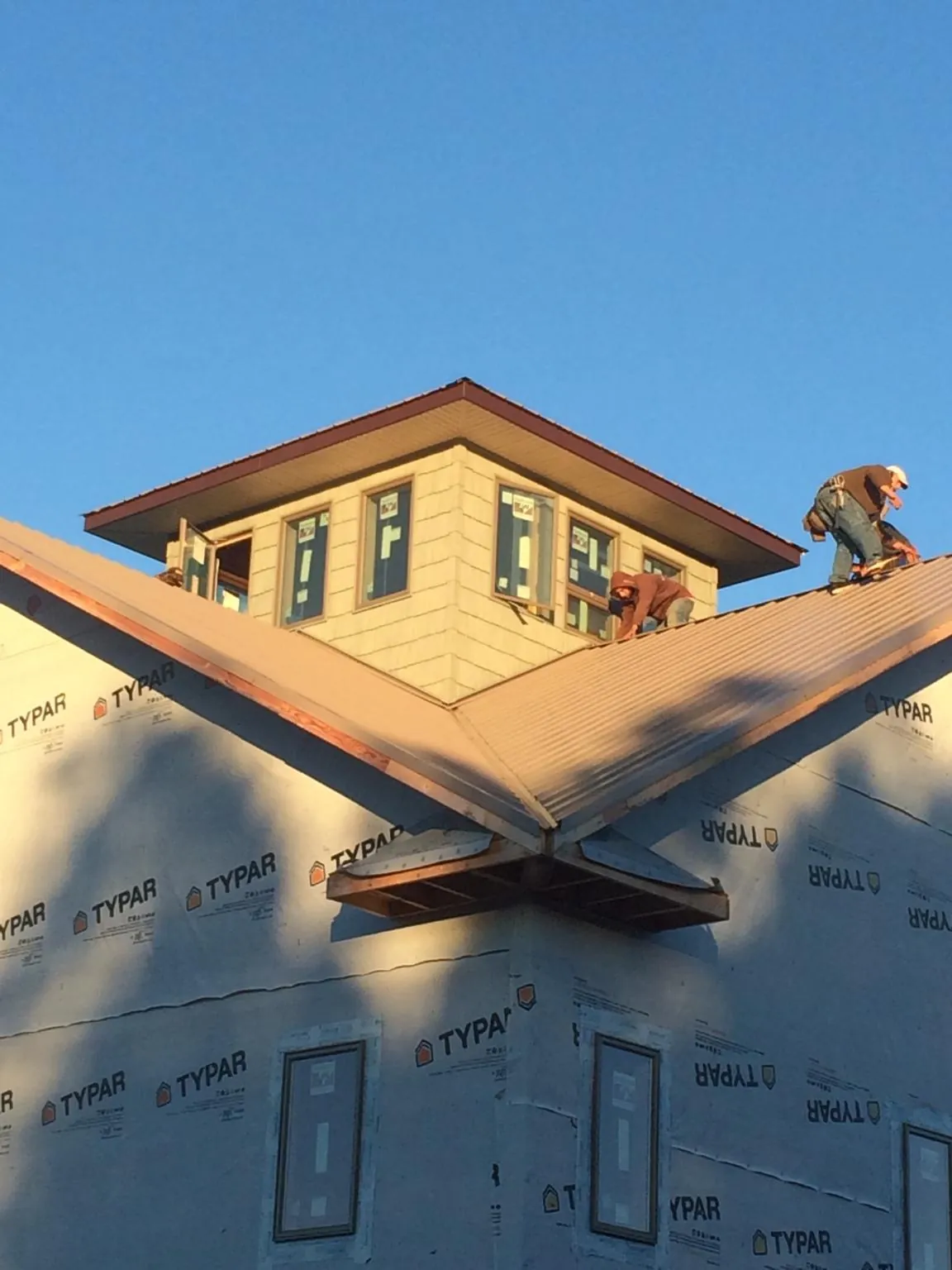 Roofers working around a rooftop cupola on a new metal roof at sunset — Roof Waterproofing in Brandon by Roofing Brothers